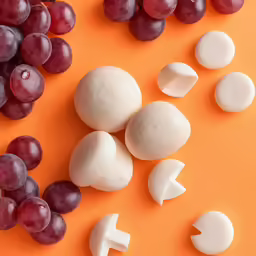 an assortment of fruit and cheese on a orange surface