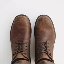 a person is wearing brown shoes on a white background