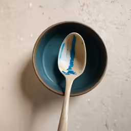the blue bowl has a spoon in it