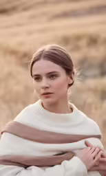 a woman wrapped in a blanket looks at the camera