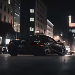 a black sports car driving down a road in the dark