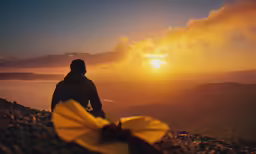 the man is standing on the top of the mountain at sunset