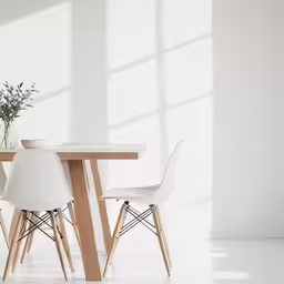 the wood table has two chairs and a vase with flowers on it