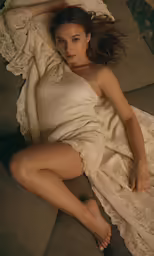 a young woman lays on the couch under a white blanket