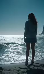 woman standing at the beach looking at the water