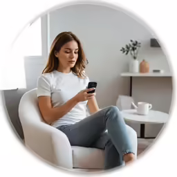a woman sitting in a chair and looking at her cell phone