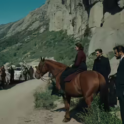 people stand on the side of the road next to a large horse