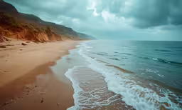 a cloudy sky hangs over a beach next to the ocean