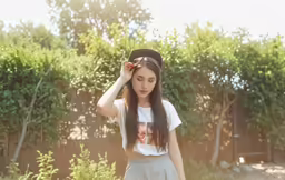 young woman wearing white shirt and skirt standing next to fence