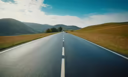 the view down an empty country road with hills in the background