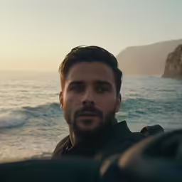 a man sitting on top of a boat next to the ocean