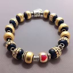an artful gold and blue beaded bracelet,a bracelet with various beads and charms