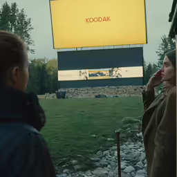 two women are talking on the phone next to a billboard