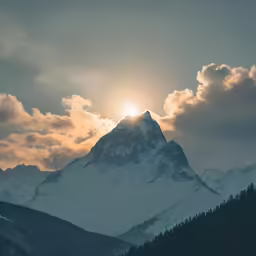 a mountain with sun going through the clouds