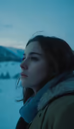 a woman in a green jacket and a snowy hill