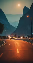 the sun rises over the mountains behind cars driving