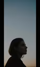 a woman looking away as the sun goes down