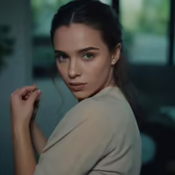a young woman wearing an elegant blouse looks ahead