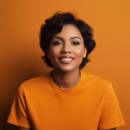 smiling woman with dark skin against an orange background