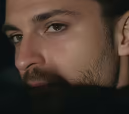 a man looks straight ahead with a beard