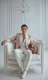 a beautiful woman wearing white sitting on a chair