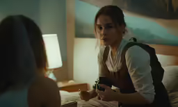 a woman holding a gun on a bed