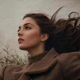 woman with flying hair on her head leaning against wall