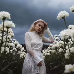 a woman in a white dress is standing in a field of flowers