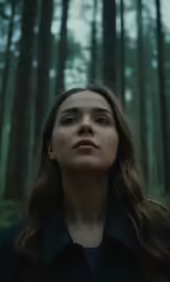 a woman standing in the woods looking up
