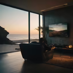 a man sitting on a couch looking out at the ocean