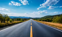 an empty highway runs between several mountains and scrub brush