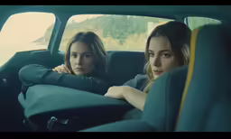 two beautiful women sitting in a car facing forward