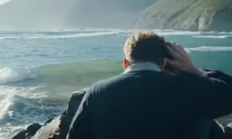 a man talking on his cell phone on a rocky shore