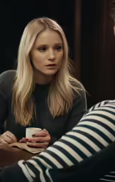 two people sitting at a table with one holding a cup