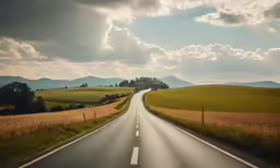 the road is winding through the countryside under some clouds