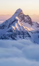 the sun is setting on a mountain top with low lying fog
