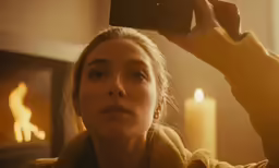 a woman with a towel holding up a camera to her face