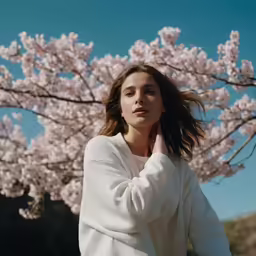a woman leaning on a tree with blossoms in the background