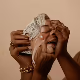 a woman in her makeup with gold bracelets on