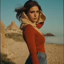 a woman standing on the sand with a hood over her head