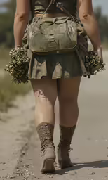 a woman in dress walking down a dirt road