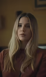 the woman is wearing a brown shirt and sitting