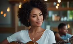 an african american woman sitting and playing a guitar