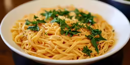 a white bowl of pasta and garnished with fresh parsley