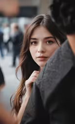 a girl is posing outside with her hand under her ear