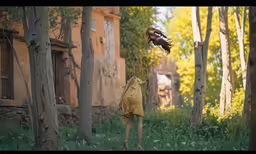 a bird of prey on a persons arm in front of a building