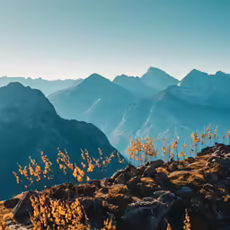 a man stands on a rocky hill top overlooking the mountain range