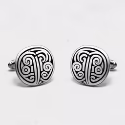 two cufflinks with designs on them sitting side by side