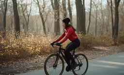 a person in a red top riding a bike on a paved road