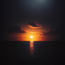 the sun setting over the water near some clouds
